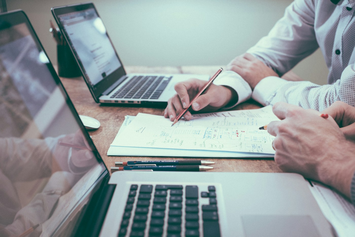 Illustrative photograph of professionals reviewing paper documents beside laptops